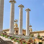 青空の下に立つ高い石柱と階段のある壮大な建物の外観。