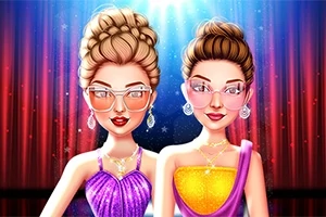舞台の前でサングラスをかけた2人の女性が華やかなドレスを着て立っている。