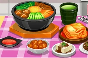 ピンクのテーブルクロスの上に鍋料理と様々な料理と緑茶が並んでいる。