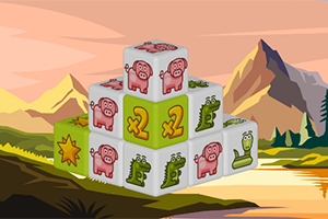 積み重ねられたブロックに豚やワニの絵が描かれており、背景に山と湖がある風景。