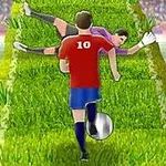 赤いユニフォームのサッカー選手が芝生の上をボールでドリブルし、倒れたゴールキーパーをかわしている場面。