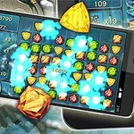 スマートフォンの画面にカラフルな宝石が並んでおり、赤い目の骸骨が近くにある。