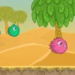 砂漠の風景の中で、ピンク、緑、紫のふわふわした生き物が並んでいる。