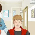 病院の廊下で医療スクラブを着た看護師が車椅子の若い男の子と一緒にいるイラスト。
