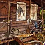 木造の小屋の前に、釣り具やランタンなどの道具が掛けられている。