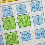 数字が書かれた青と緑の9つの四角が紙に配置されている。