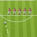 サッカーのフィールドで赤いユニフォームを着た5人が壁を作り、ボールが曲がった軌道で向かっている様子。