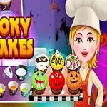 お化けやジャック・オ・ランタンのデコレーションが施されたカラフルなカップケーキを持つシェフの女性。