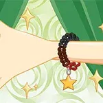 緑色の背景の前に星のチャームが付いたブレスレットを付けた腕。