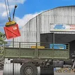 トラックが倉庫前に停まり、クレーンで赤いコンテナが運ばれている様子。