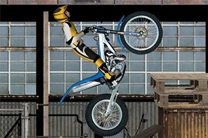 黄色いヘルメットとスーツを着たバイクライダーが、バイクでウィリーして木製の足場を越えようとしている。